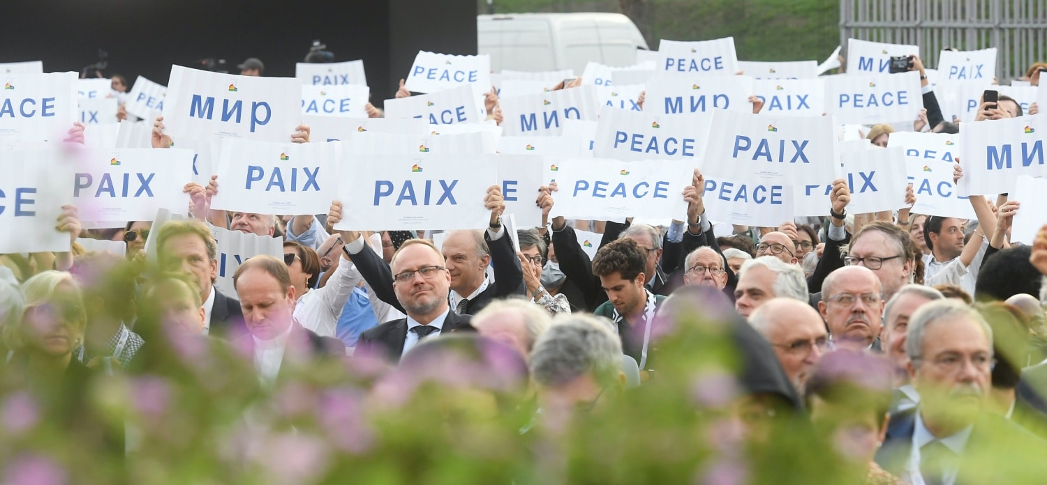 People gathered with Pope Francis and other religious leaders at Rome's Colosseum Oct. 25, 2022, hold up signs in various languages calling for peace. (CNS photo/Vatican Media)